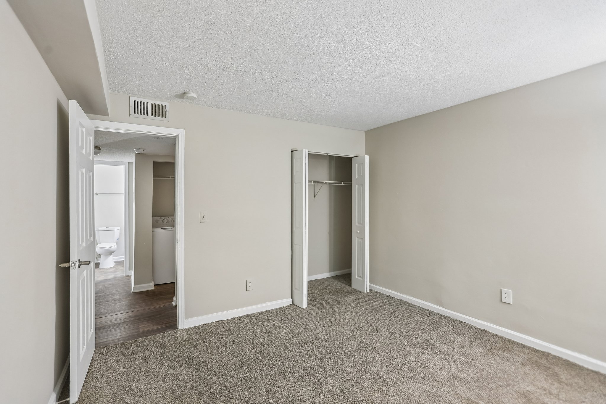 A room with a carpeted floor and a white door.